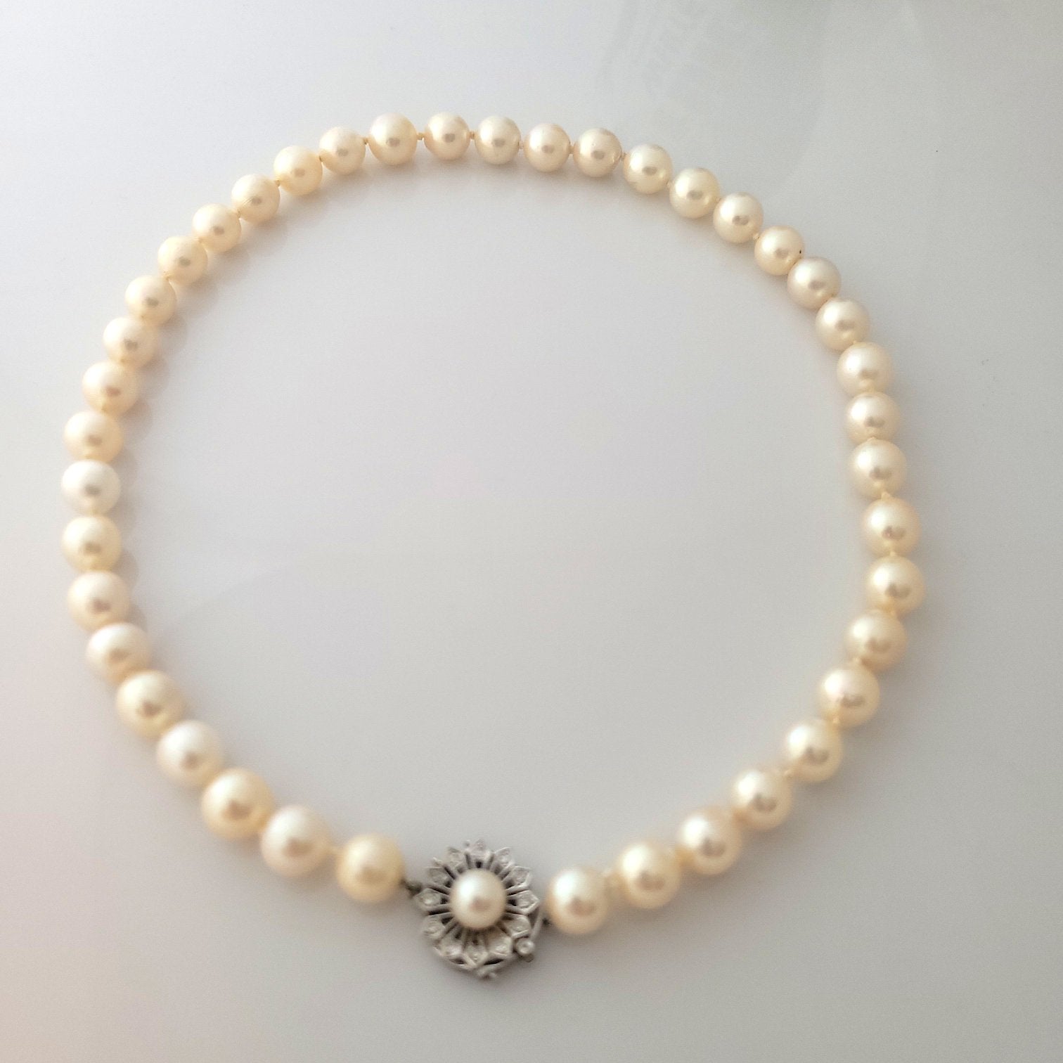 Sold at Auction: Three-strand pearl necklace with emerald and diamond clasp